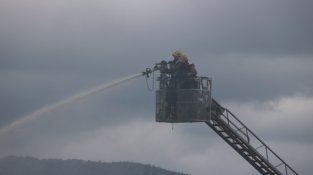 Intervenció dels bombers amb una escala sobre el teulat de la fàbrica