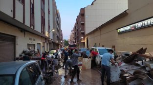 Bombers i voluntaris netejant un dels carrers d'Algemesí