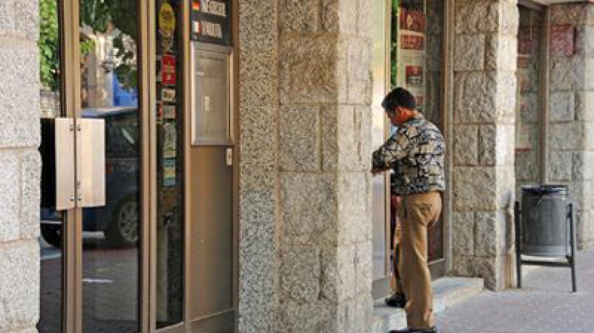 Un ciutadà retira diners d'un caixer automàtic al carrer Major de la Jonquera