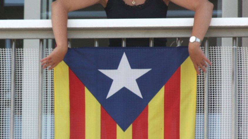 Una veïna penja una estelada en un balcó