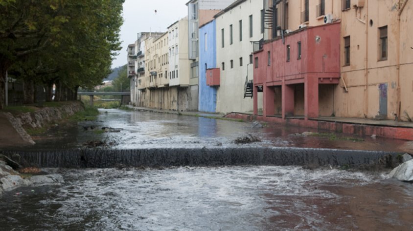 El riu Llobregat, amb l'aigua negre per l'efecte de les cendres, al seu pas pel tram urbà