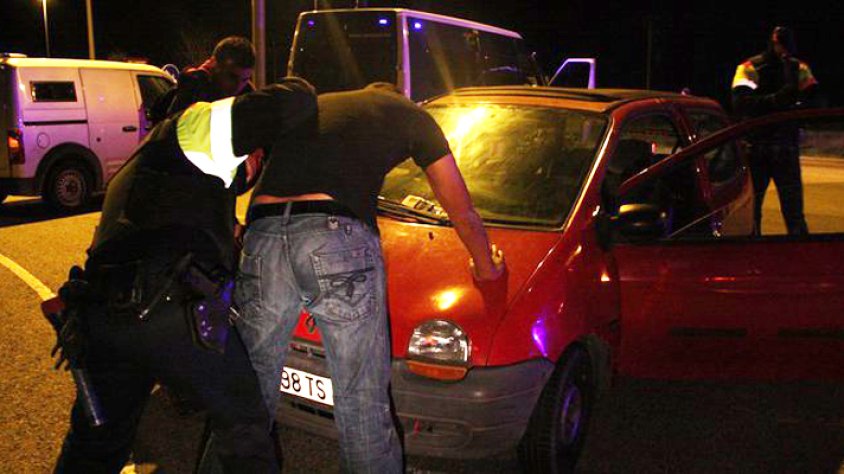 Un agent escorcollant un dels ocupants d'un vehicle en un dels controls