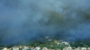 Centre urbà en primer terme. Al fons i sota el fum la Torre del Carmanxel