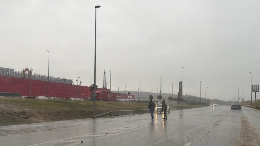 Dos vianants creuen en un dia de pluja la carretera N-II a la Jonquera